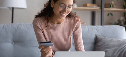 chica con tarjeta en la mano y ordenador