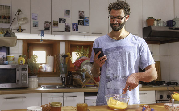 chico cocinando con una mano y el móvil en la otra