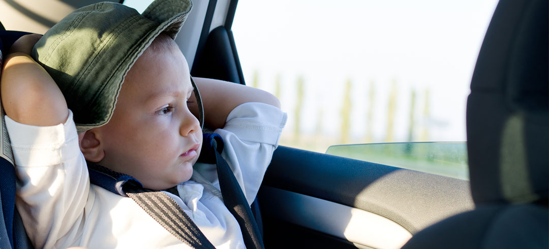 Niño pequeño viajando en la parte de atrás de un coche con su silla
