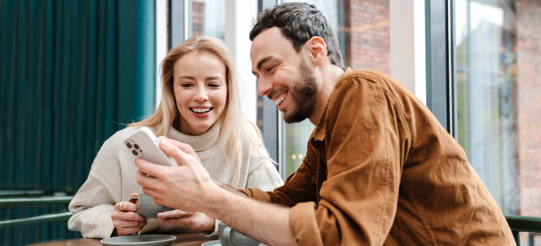 Dos personas riéndose mientras ven algo juntos en un iPhone