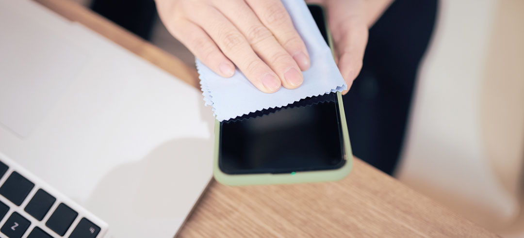 Persona limpiando la pantalla de un teléfono con un paño de microfibra