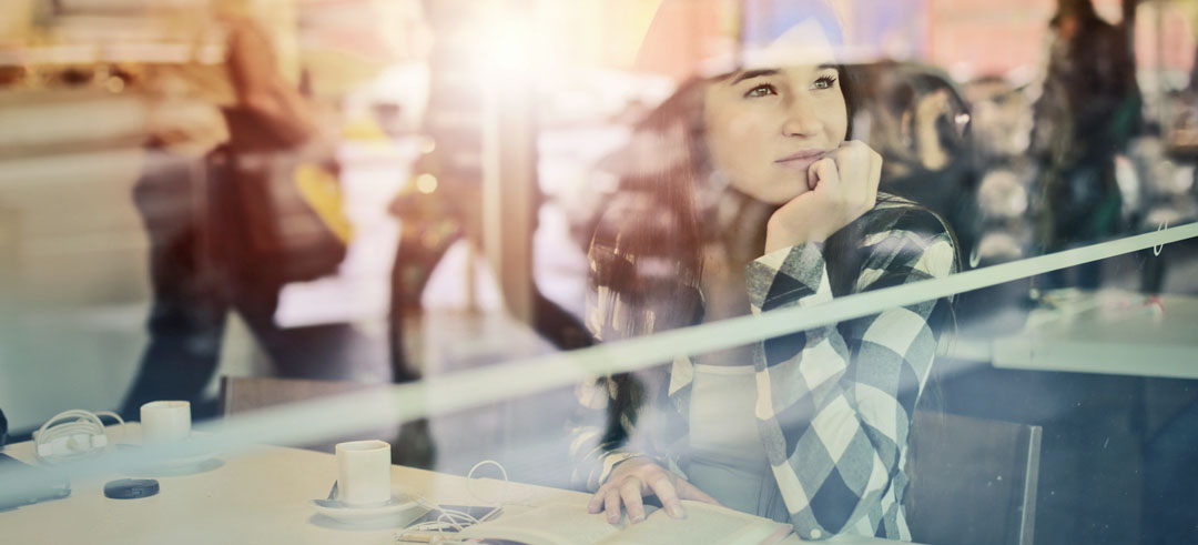 Chica mirando a través de la ventana de una cafetería